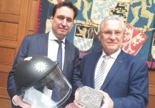 Bild von Justizminister Georg Eisenreich und Innenminister Joachim Herrmann mit einem Helm, der 2013 bei Krawallen um die Rote Flora in Hamburg von einem bayerischen Polizisten getragen und schwer beschädigt wurde