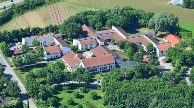 Luftaufnahme: Blick auf mehrere Gebäude, umgeben von Bäumen.