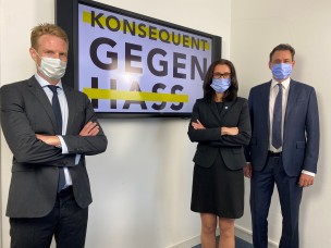 Justizminister Georg Eisenreich (r.) mit Staatsanwältin Teresa Ott und Oberstaatsanwalt Klaus-Dieter Hartleb vor dem Logo "Konsequent gegen Hass".